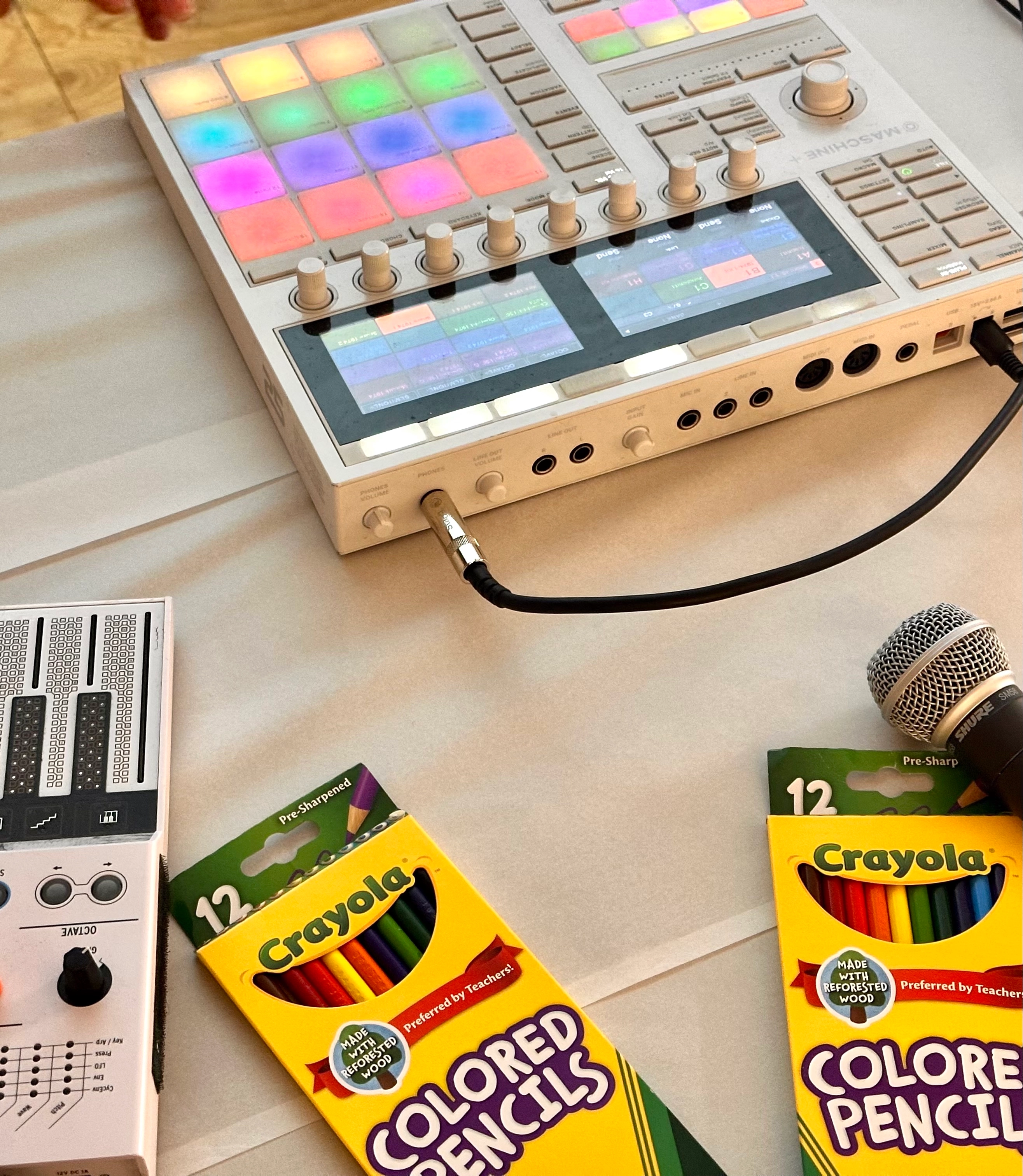 A spread of different audio equipment and colored pencils on a white tablecloth.